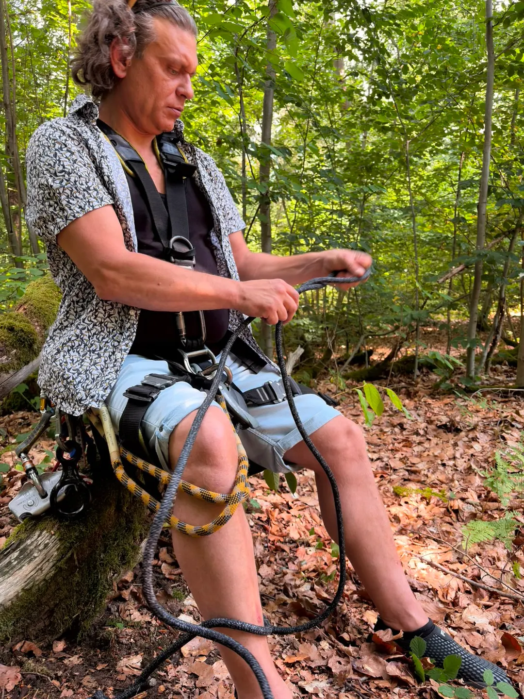 Sven Schwind sortiert sitzend ein Kletterseil, den Blick konzentriert auf die Hände gerichtet